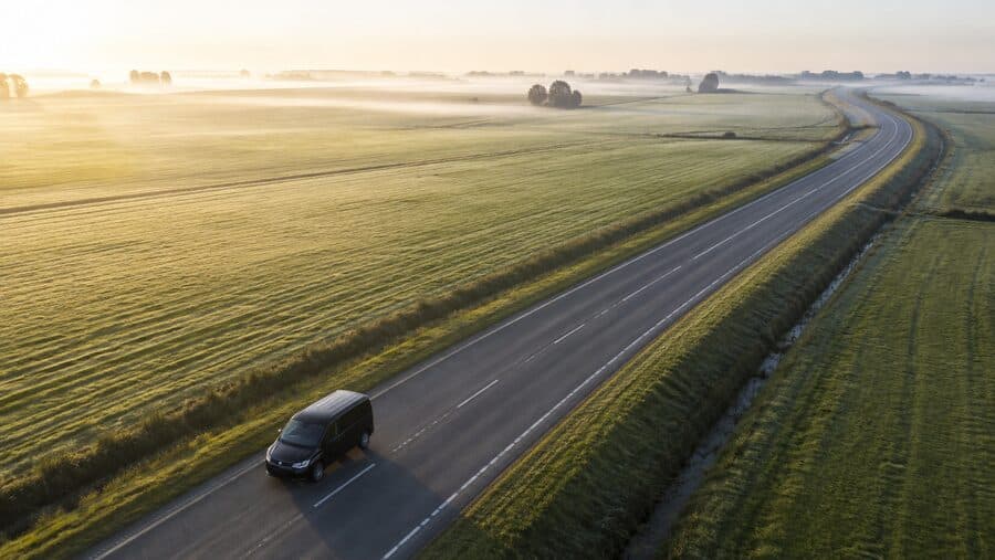 Bestelbus onderweg op een landweg bij zonsopkomst